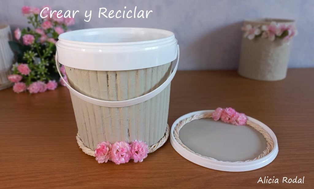 En este tutorial veremos cómo decorar un envase en forma de pote o cesta plástica, con papel periódico o revistas viejas para conseguir un efecto como de madera. Es la decoración de un recipiente, tarro o tarrina de helado o yogur, haciendo la imitación de tablas o palos de madera. DIY