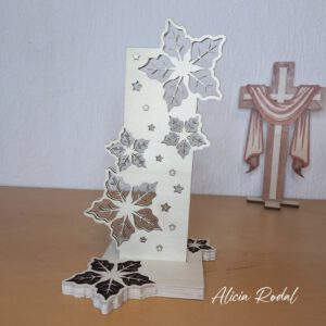 Pieza decorativa navideña que aúna arte, creatividad y funcionalidad: una escultura en madera con corte láser, compuesta por dos partes verticales encajadas perpendicularmente sobre una base, con luces LED en su interior.