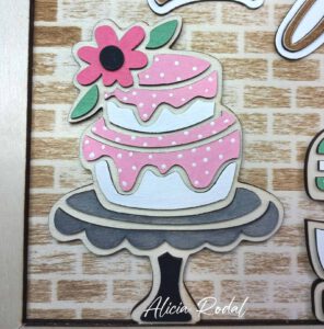 Hoy quiero compartir contigo el proceso detrás de una de mis creaciones más especiales: un cuadro de madera diseñado, cortado, grabado y pintado a mano, que representa una pequeña tienda u obrador de repostería. Esta pieza, pensada como regalo personalizado, forma parte del catálogo de mi tienda de arte y regalos personalizados, Alicia Rodal.