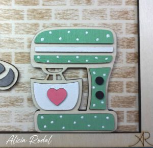 Hoy quiero compartir contigo el proceso detrás de una de mis creaciones más especiales: un cuadro de madera diseñado, cortado, grabado y pintado a mano, que representa una pequeña tienda u obrador de repostería. Esta pieza, pensada como regalo personalizado, forma parte del catálogo de mi tienda de arte y regalos personalizados, Alicia Rodal.
